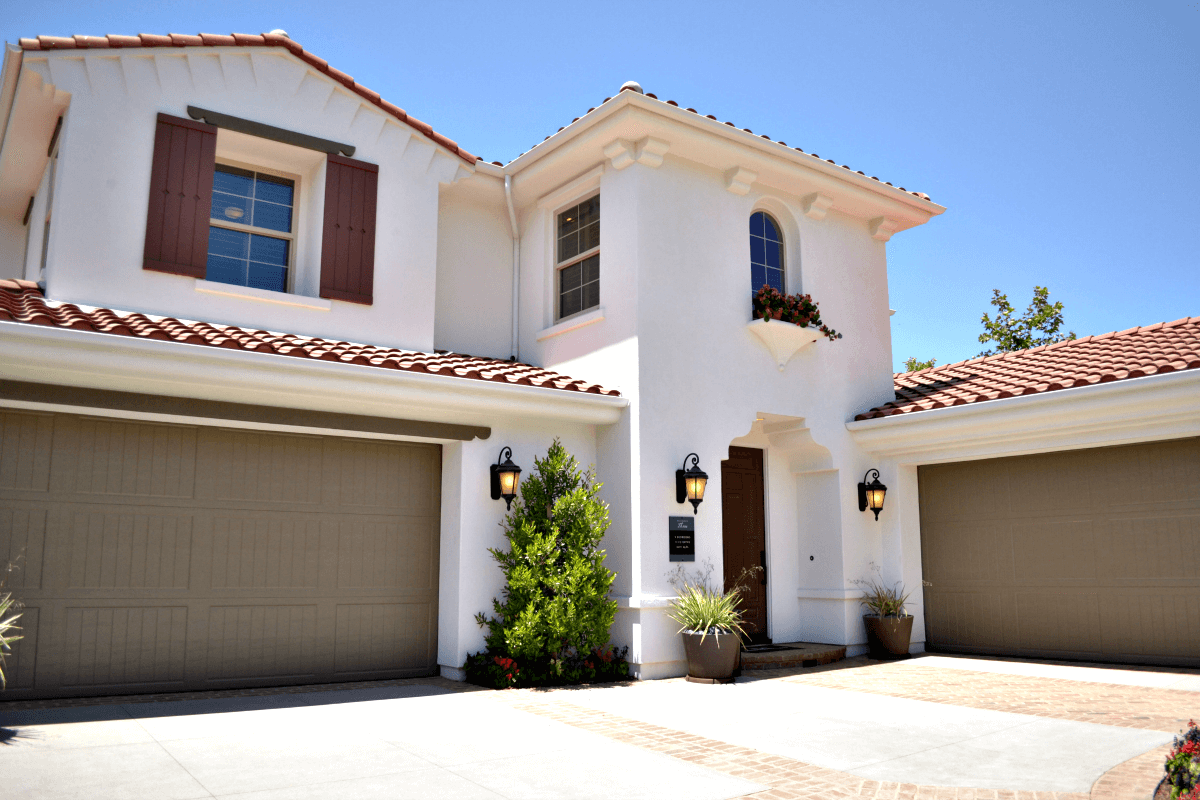 a white house with three garage doors and a red tile roof