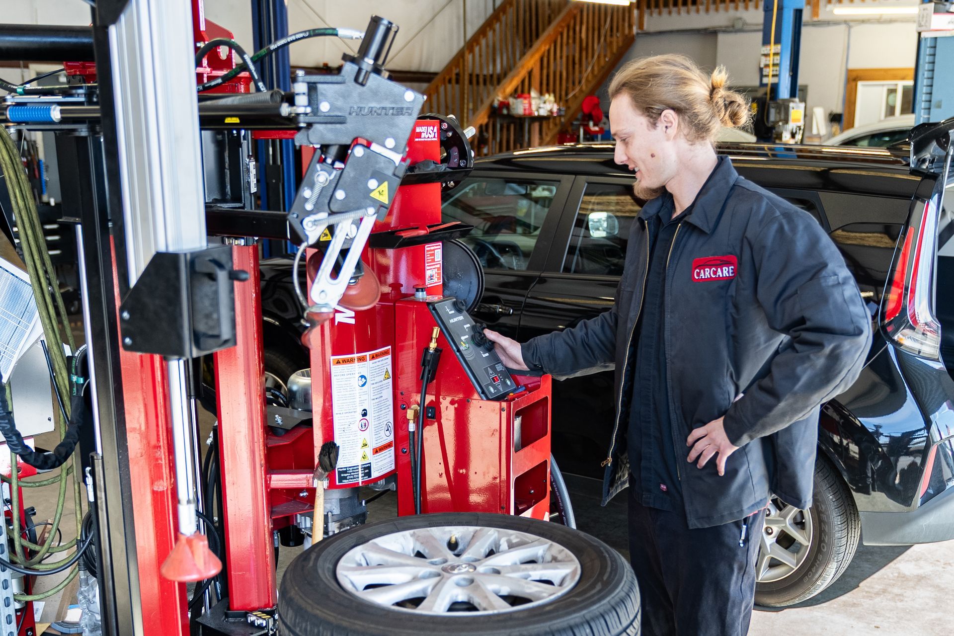 Mechanic working beside a red tire-changing machine in an auto repair shop