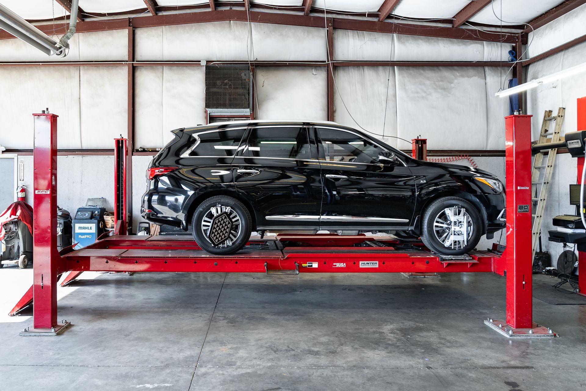 Black SUV on a red lift in an auto repair garage