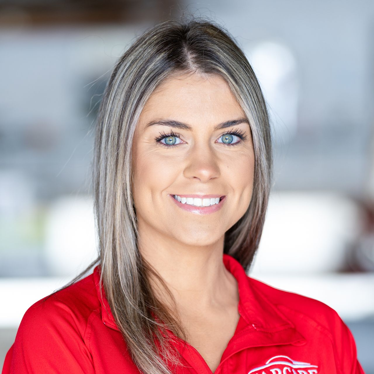 Smiling woman in a red polo shirt against a blurred office background
