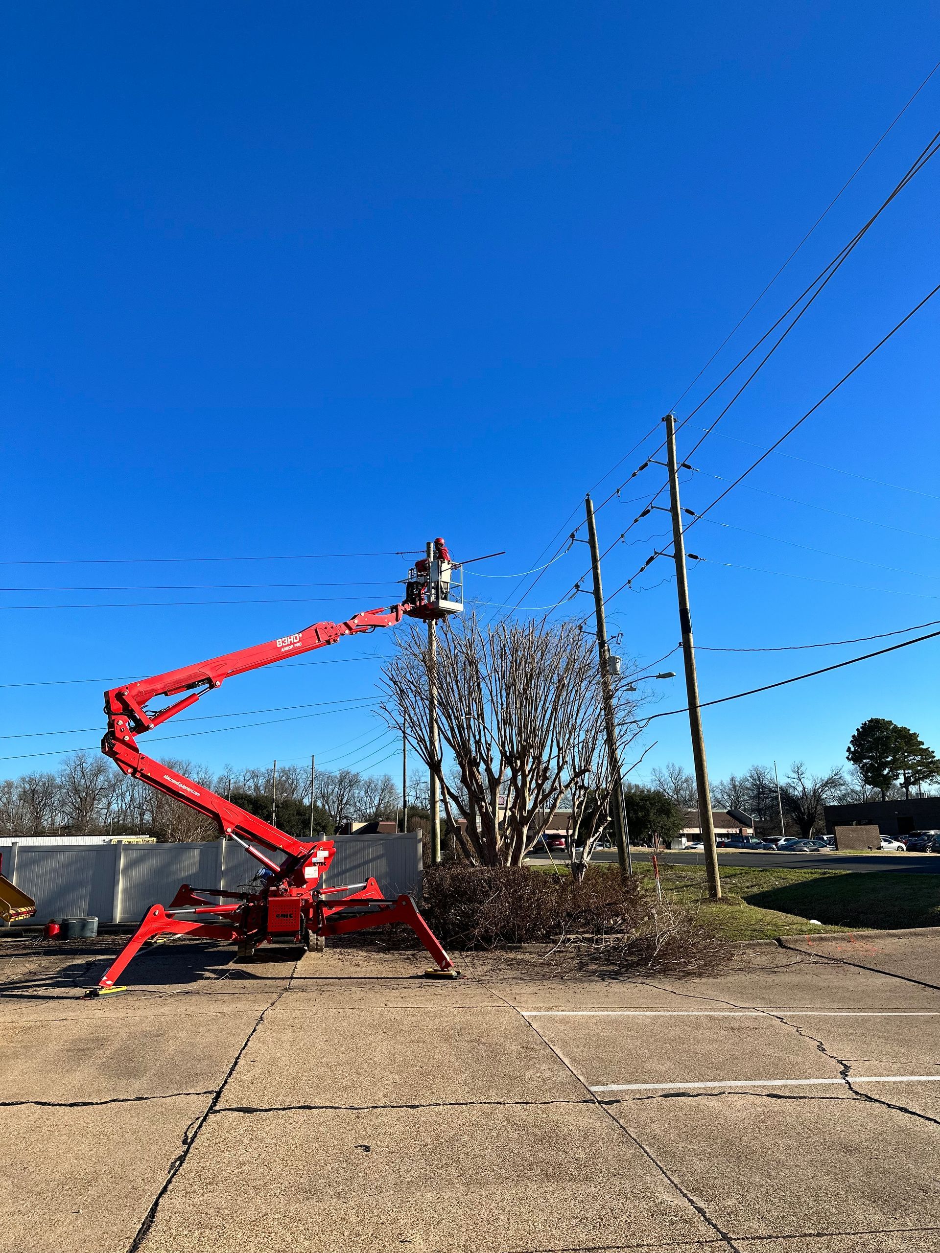 Red aerial lift working near power lines on a sunny day.