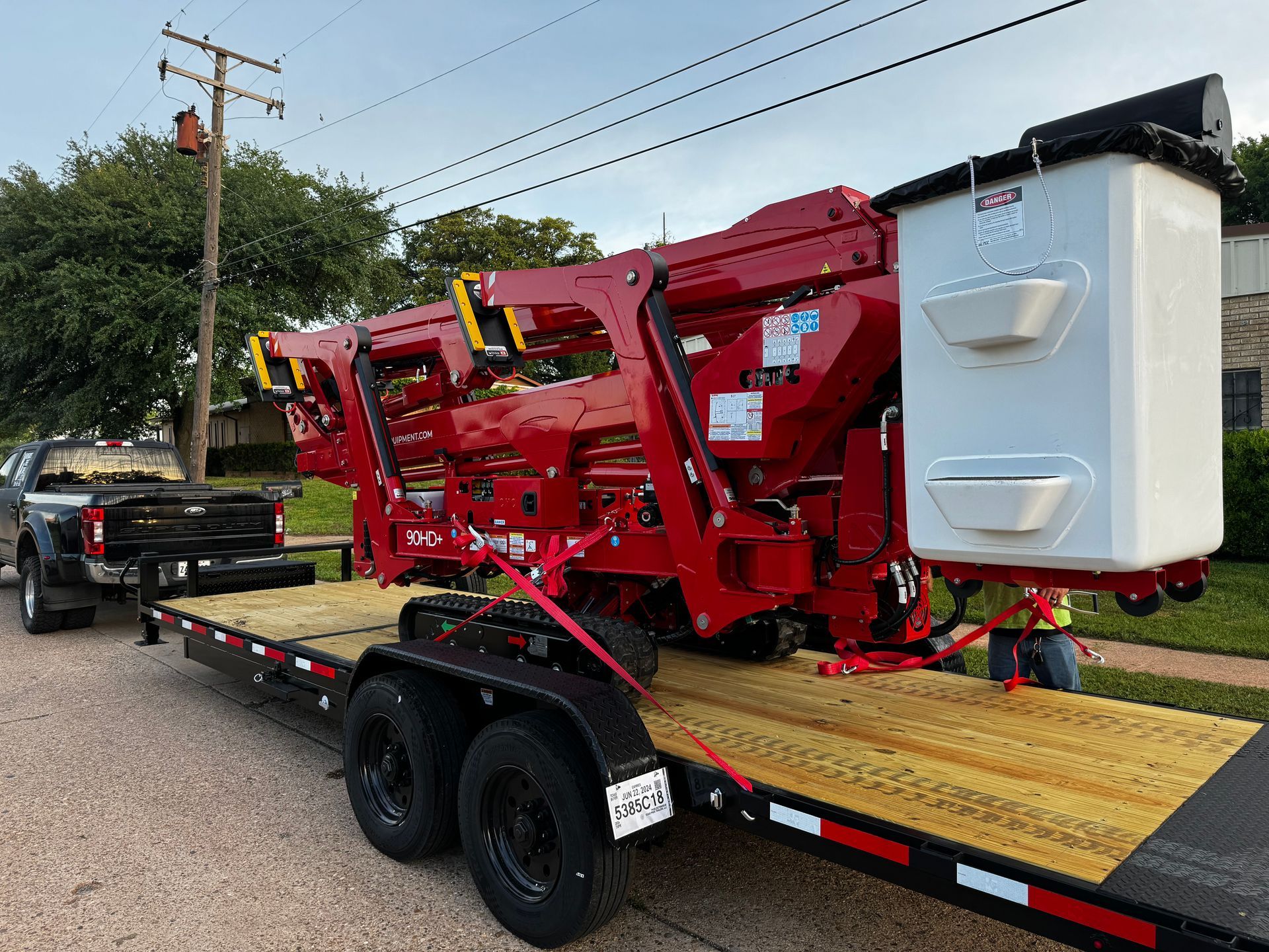 Red aerial lift on a trailer, ready for transport.