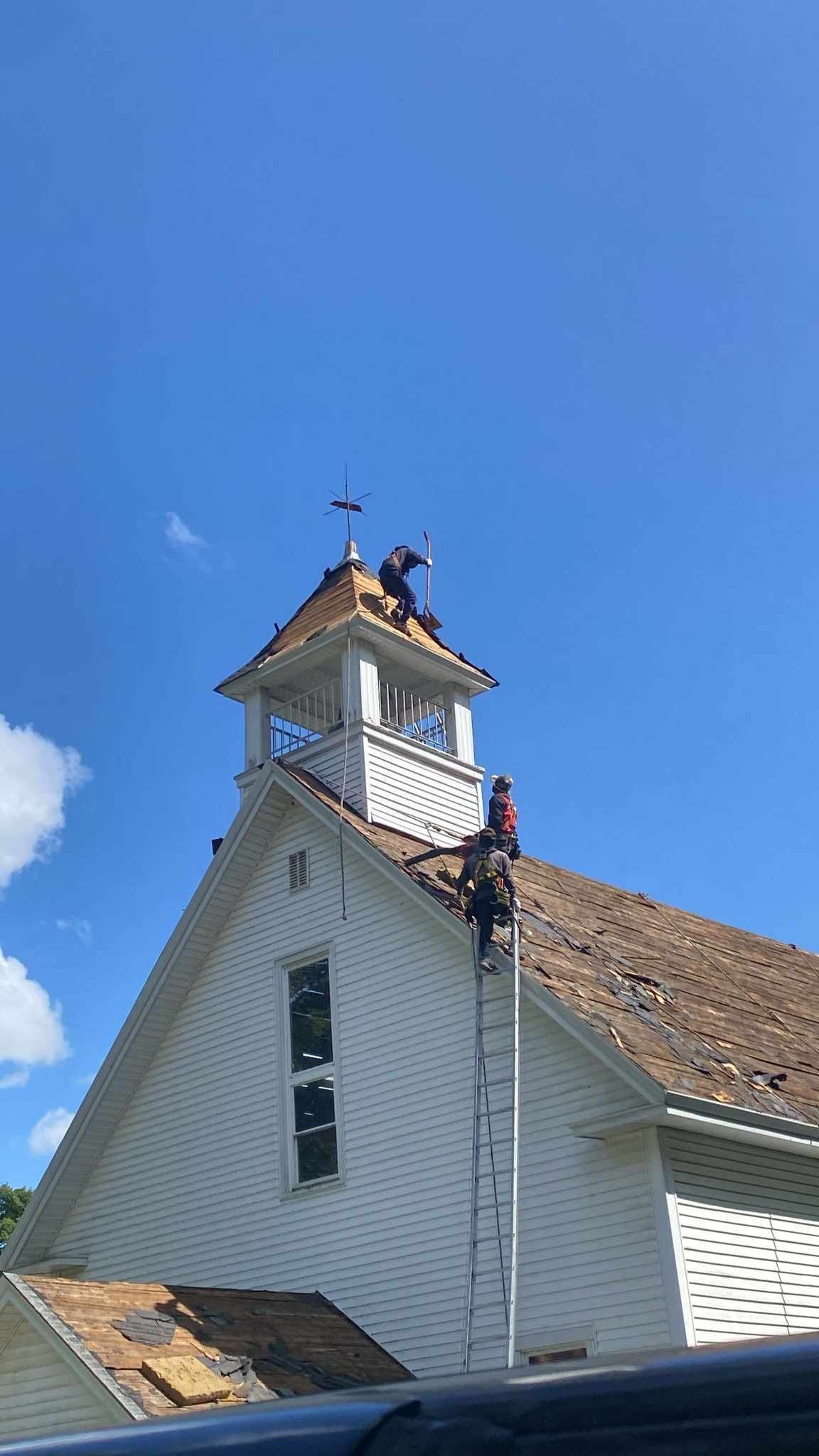 White church steeple with a small bell tower against a clear blue sky