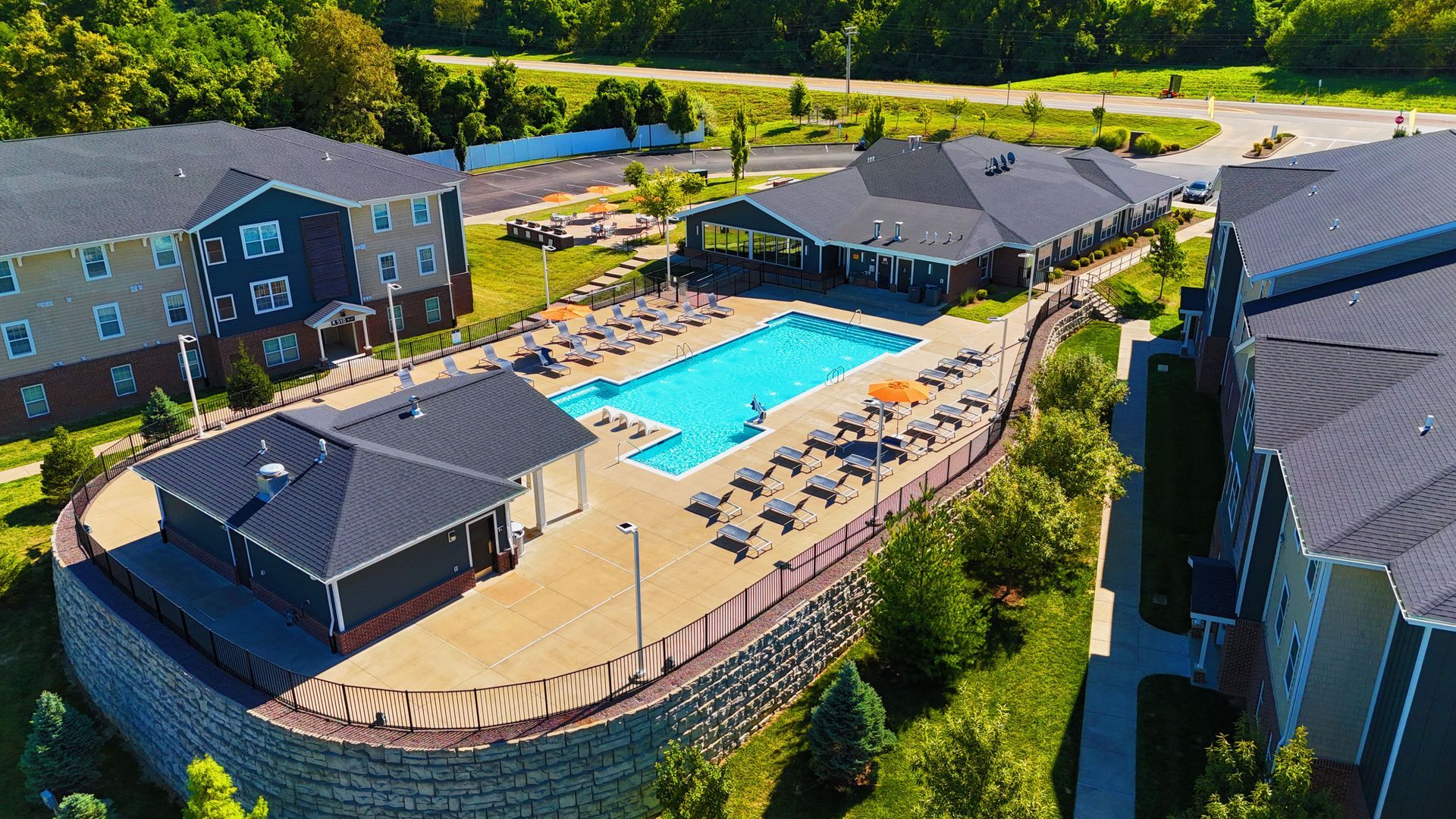 Aerial view of a pool courtyard with lounge chairs, surrounded by apartment buildings and trees