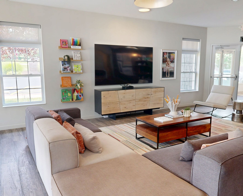 Lounge area with modular sofas, a bar with stools, and several seating areas. Neutral tones, modern design.