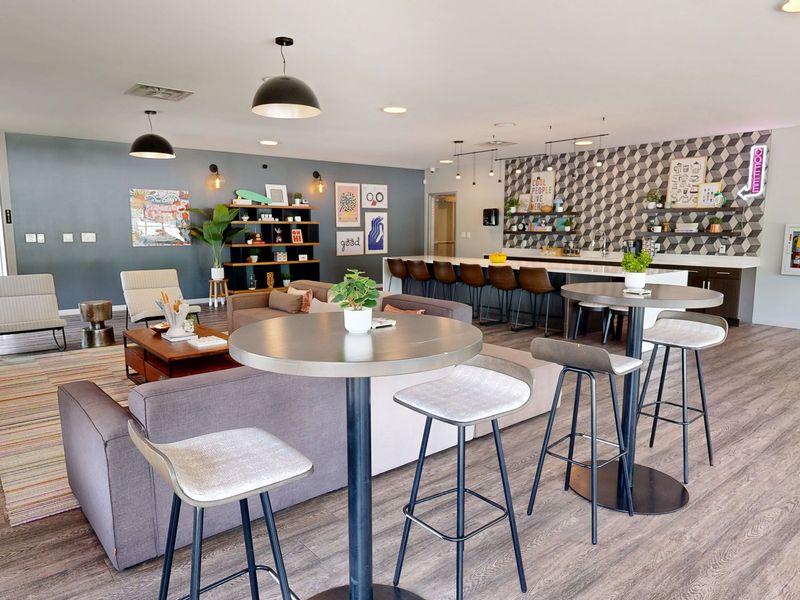 Lounge area with modular sofas, a bar with stools, and several seating areas. Neutral tones, modern design.