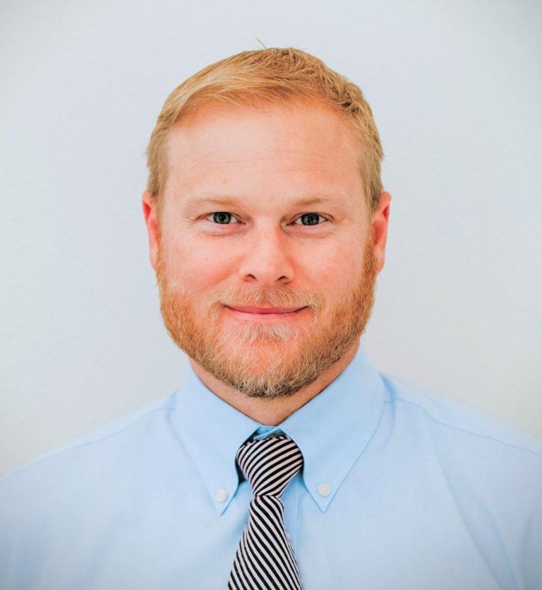 A man in a suit and tie is smiling for the camera.