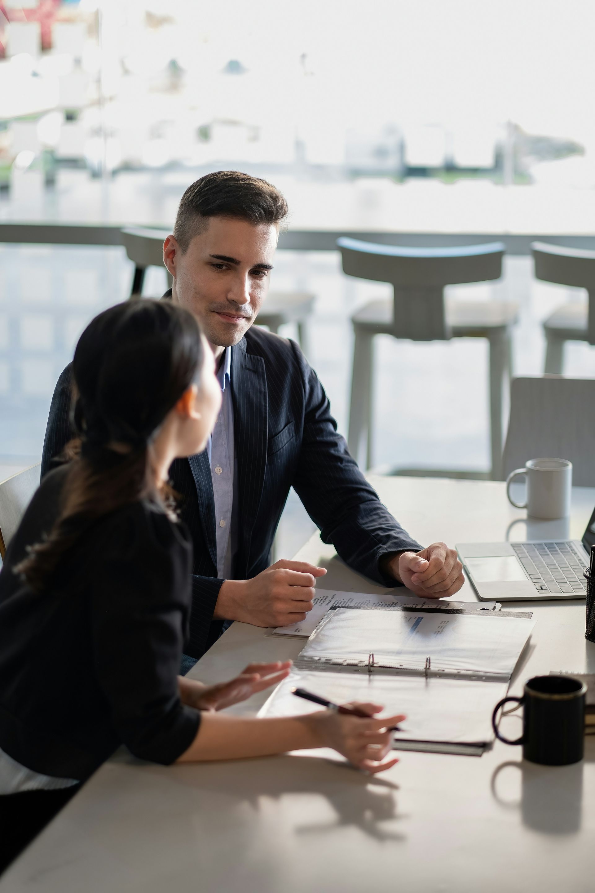 Woman and man reviewing documents at a wooden table in an office setting.