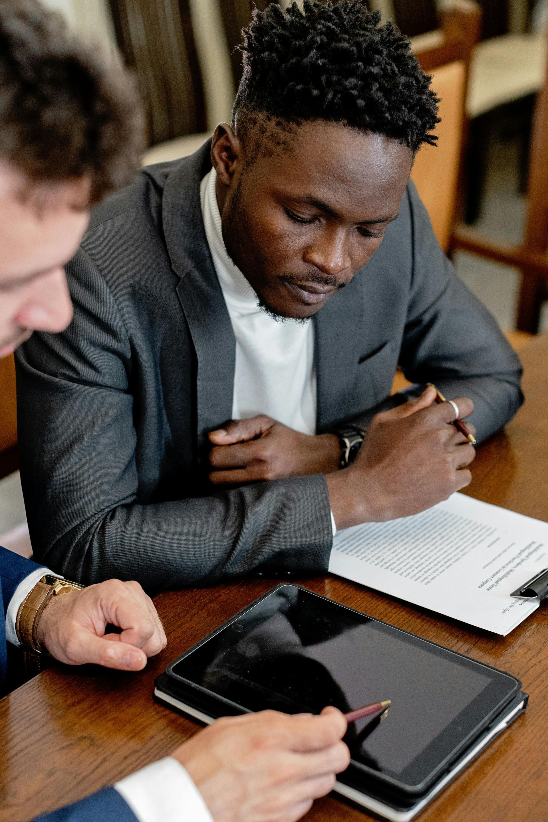 Woman and man reviewing documents at a wooden table in an office setting.