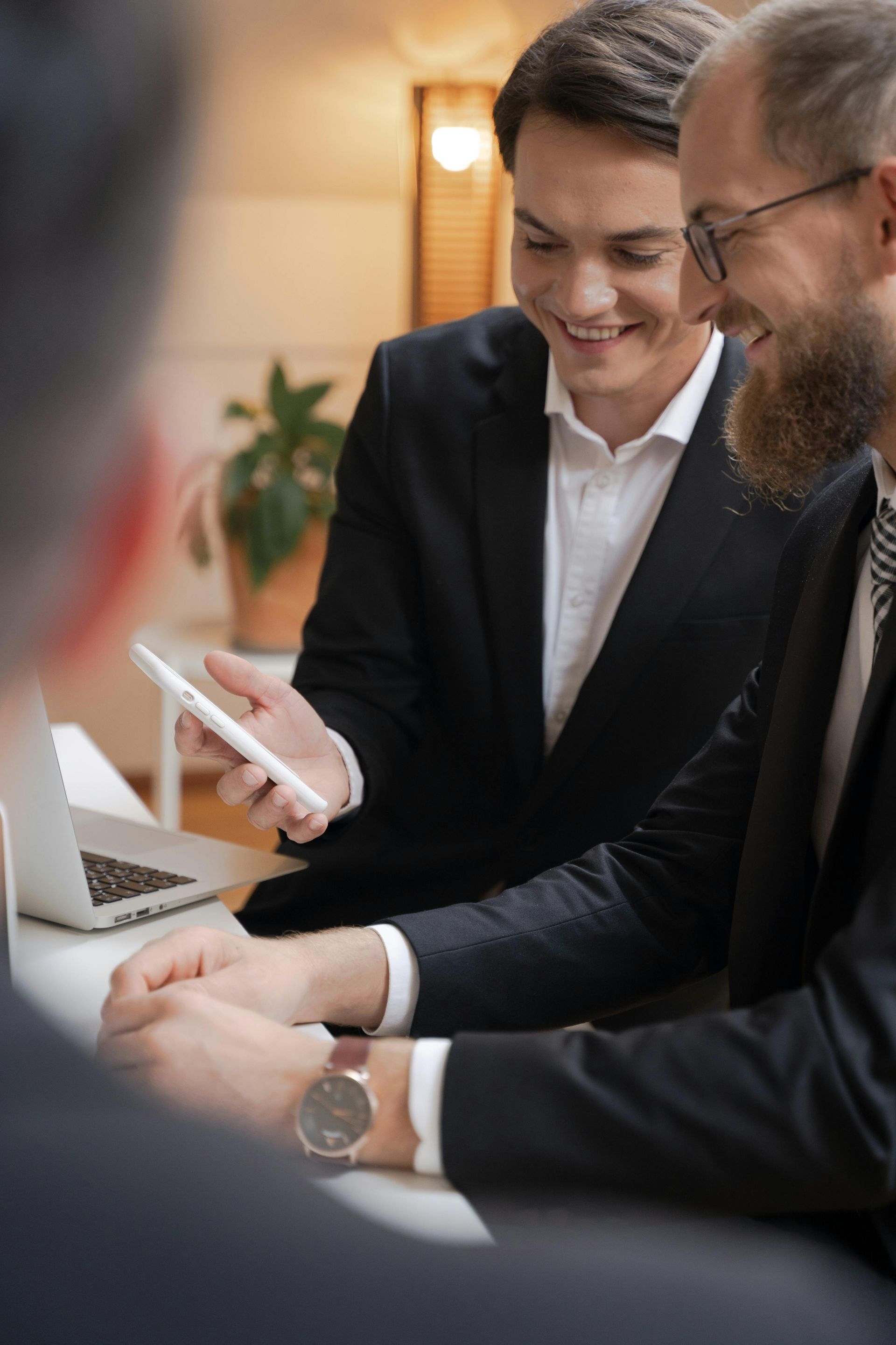 Senior couple reviews document with a professional at a table; indoor setting.