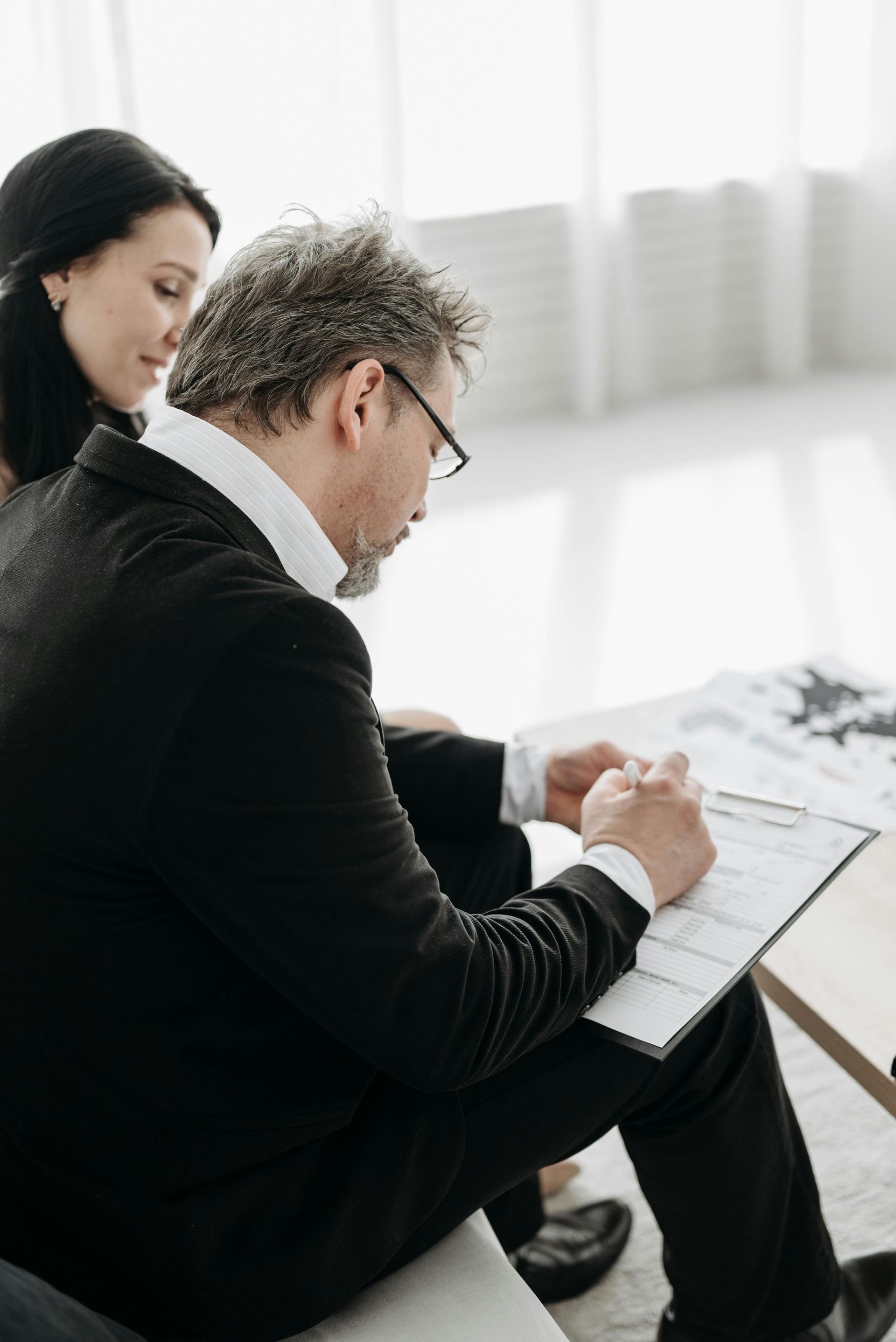 Woman and man reviewing documents at a wooden table in an office setting.