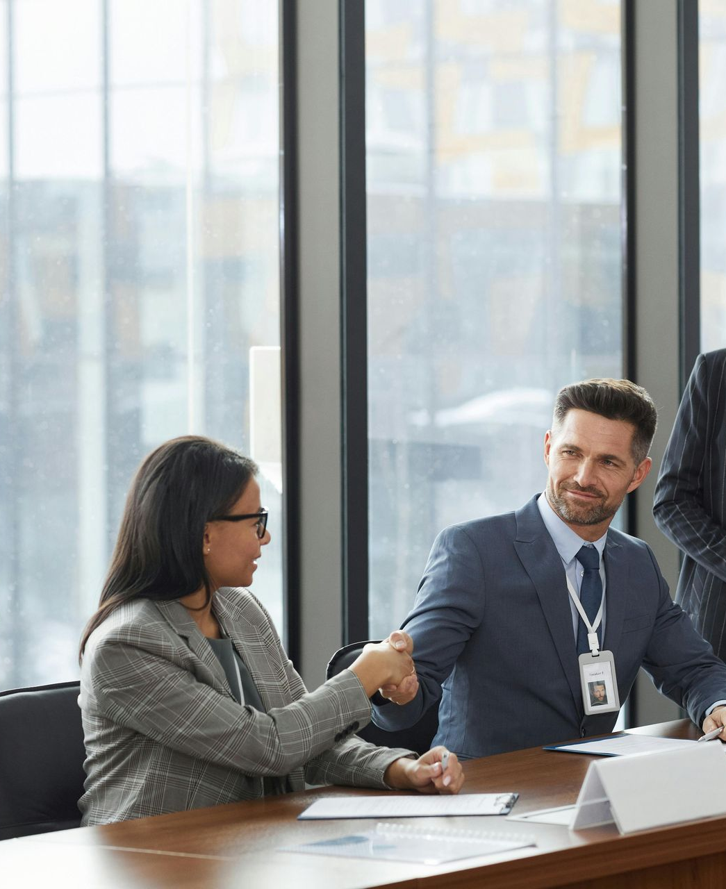 Senior couple reviews document with a professional at a table; indoor setting.
