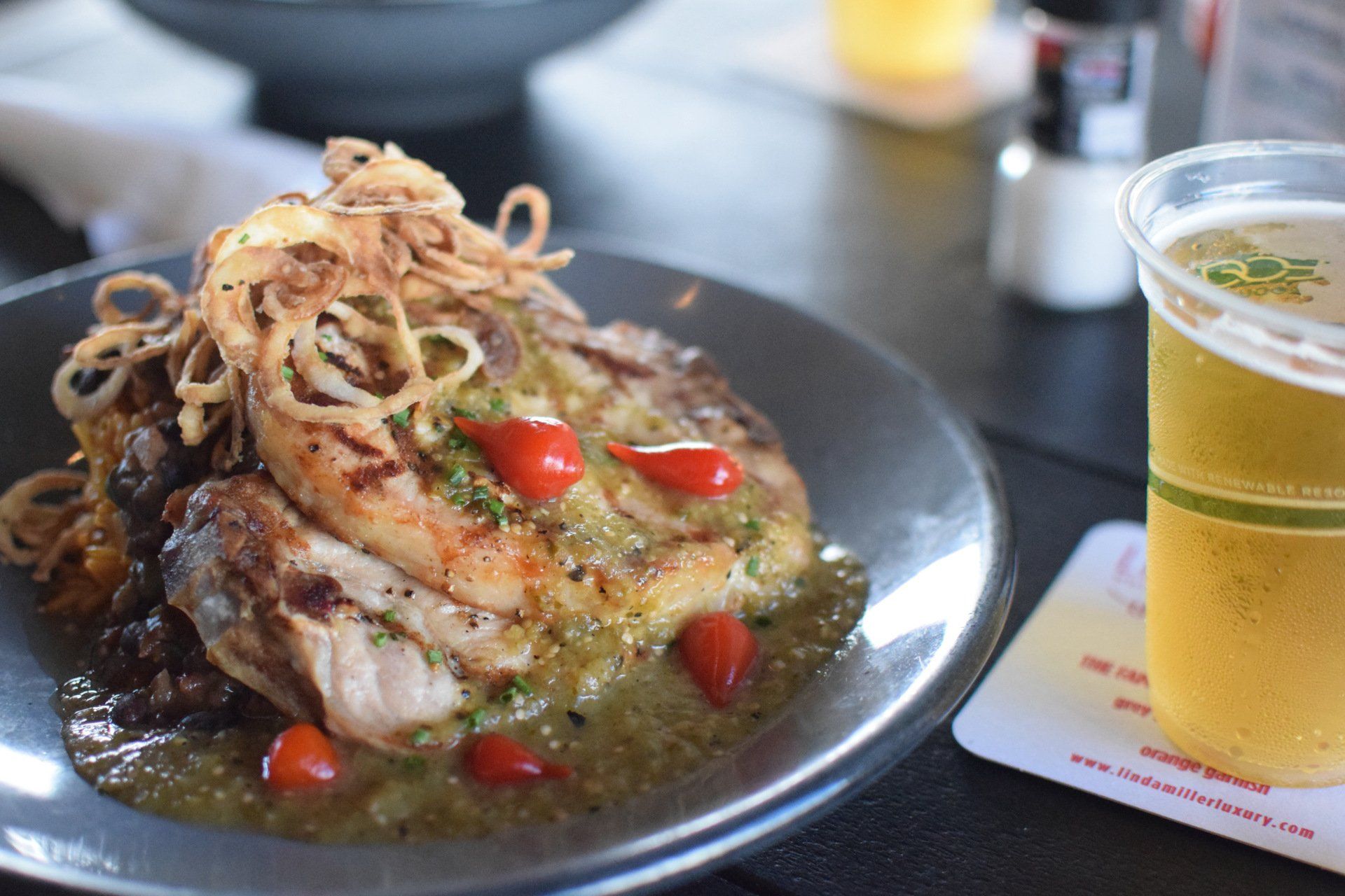 Plate of grilled fish with vegetables and a glass of beer on a table