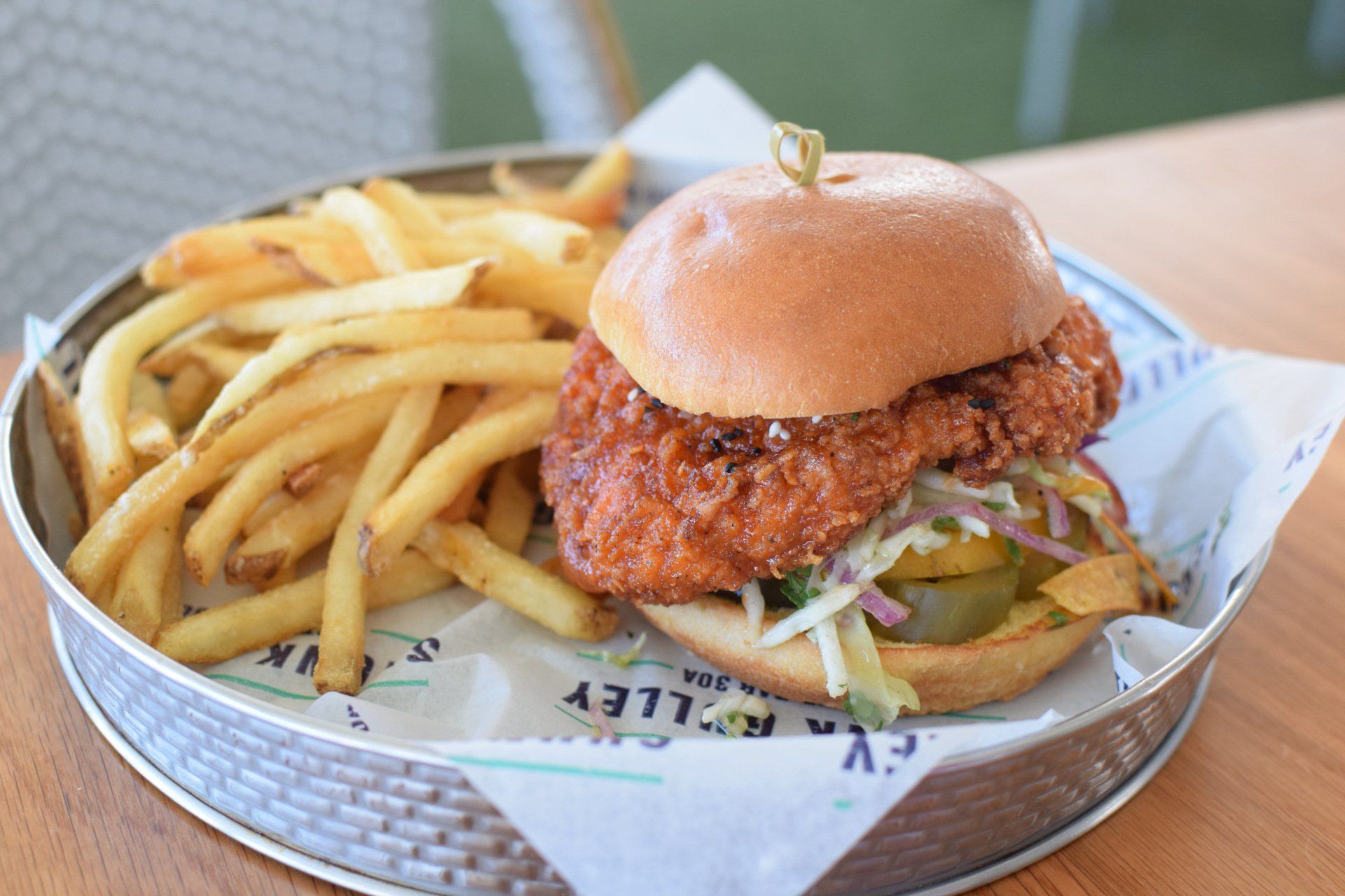 Burger and fries served in a basket on a table, with a toasted bun and crispy coating.
