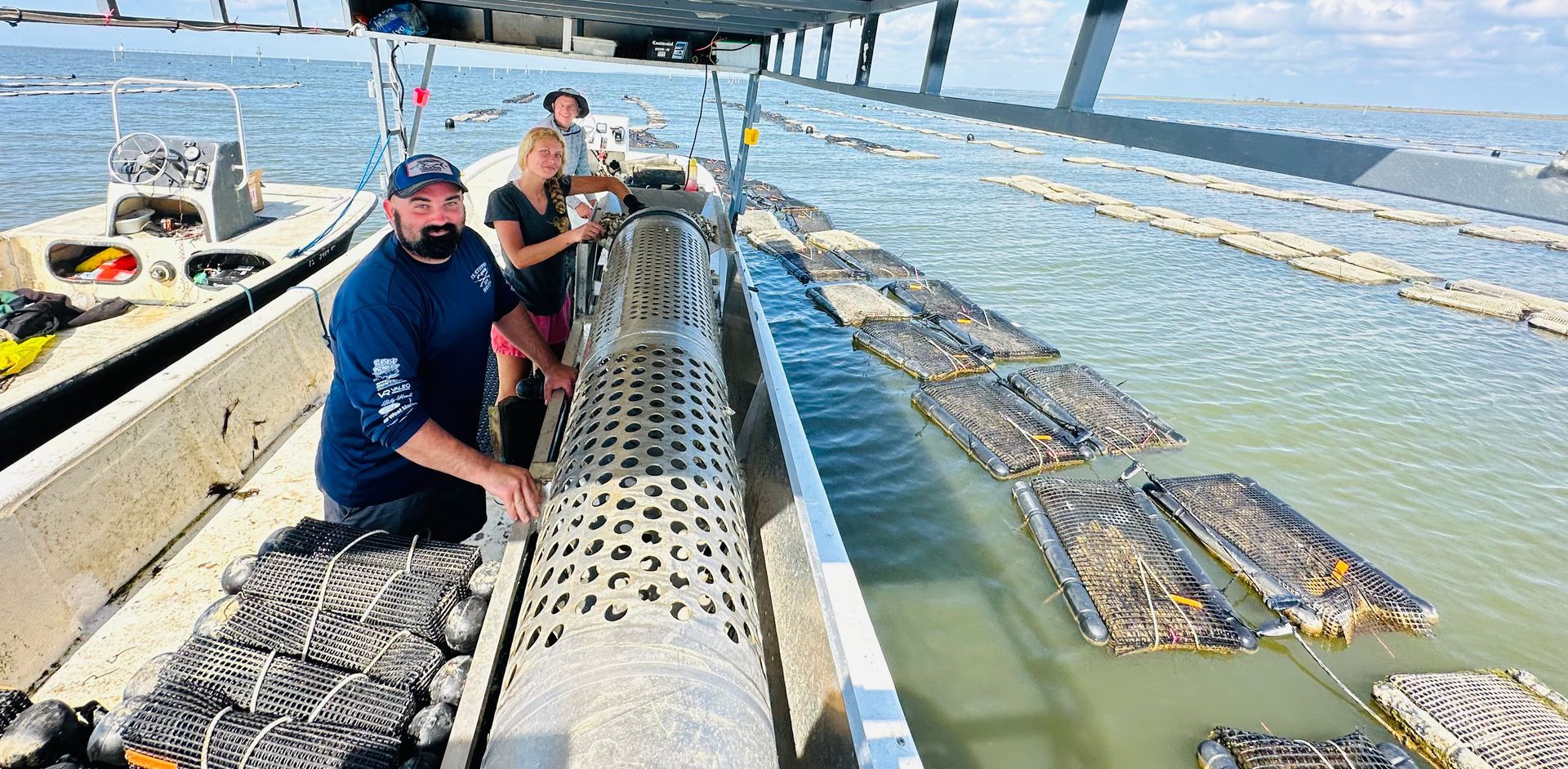 Two workers on a floating fish-farm platform handling a large net in blue water