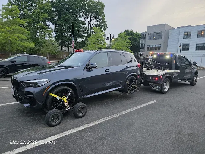 SUV with a wheel-locking device being towed on a street beside a building