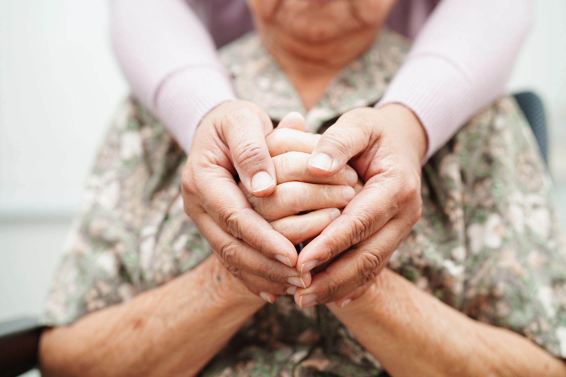 Hospice care provider gently holding an elderly patient's hands to offer comfort and support. Hospice care provider gently holding an elderly patient's hands to offer comfort and support.