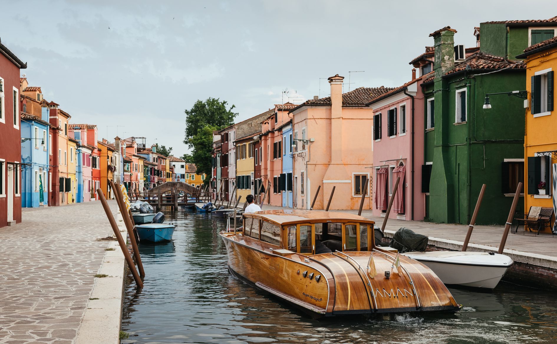 Colorful buildings line a canal with boats in Burano, Italy. Aman Venice 