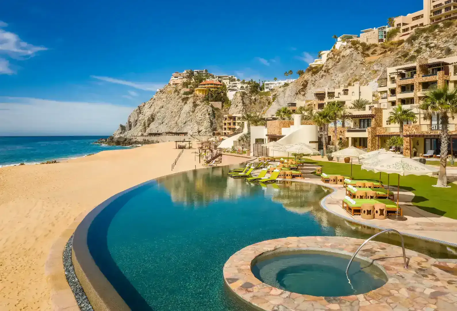 Luxury beachfront resort with turquoise pool, sandy beach, ocean, and cliffside villas under clear blue sky Waldorf Astoria Los Cabos Pedregal
