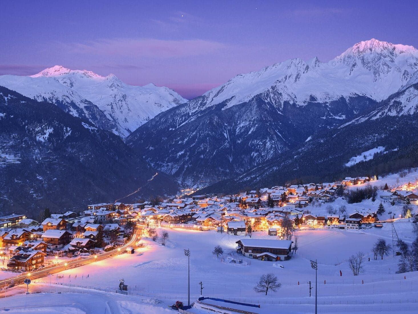Snowy mountain village at twilight with illuminated buildings. Courchevel 