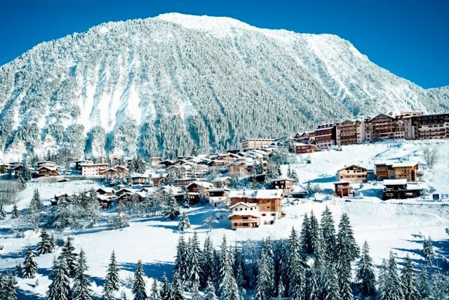 Snowy mountain town with lodges and pine trees. Courchevel