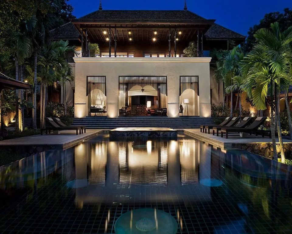 Luxury villa at night with pool and reflected lights.