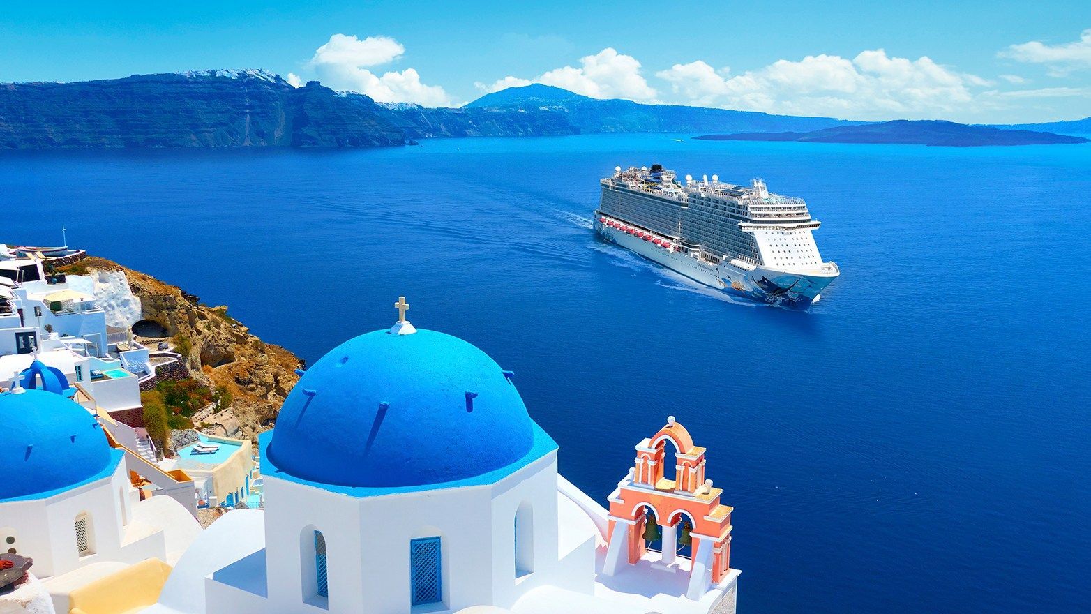 Cruise ship sailing near Santorini, Greece, with iconic blue-domed churches in the foreground.