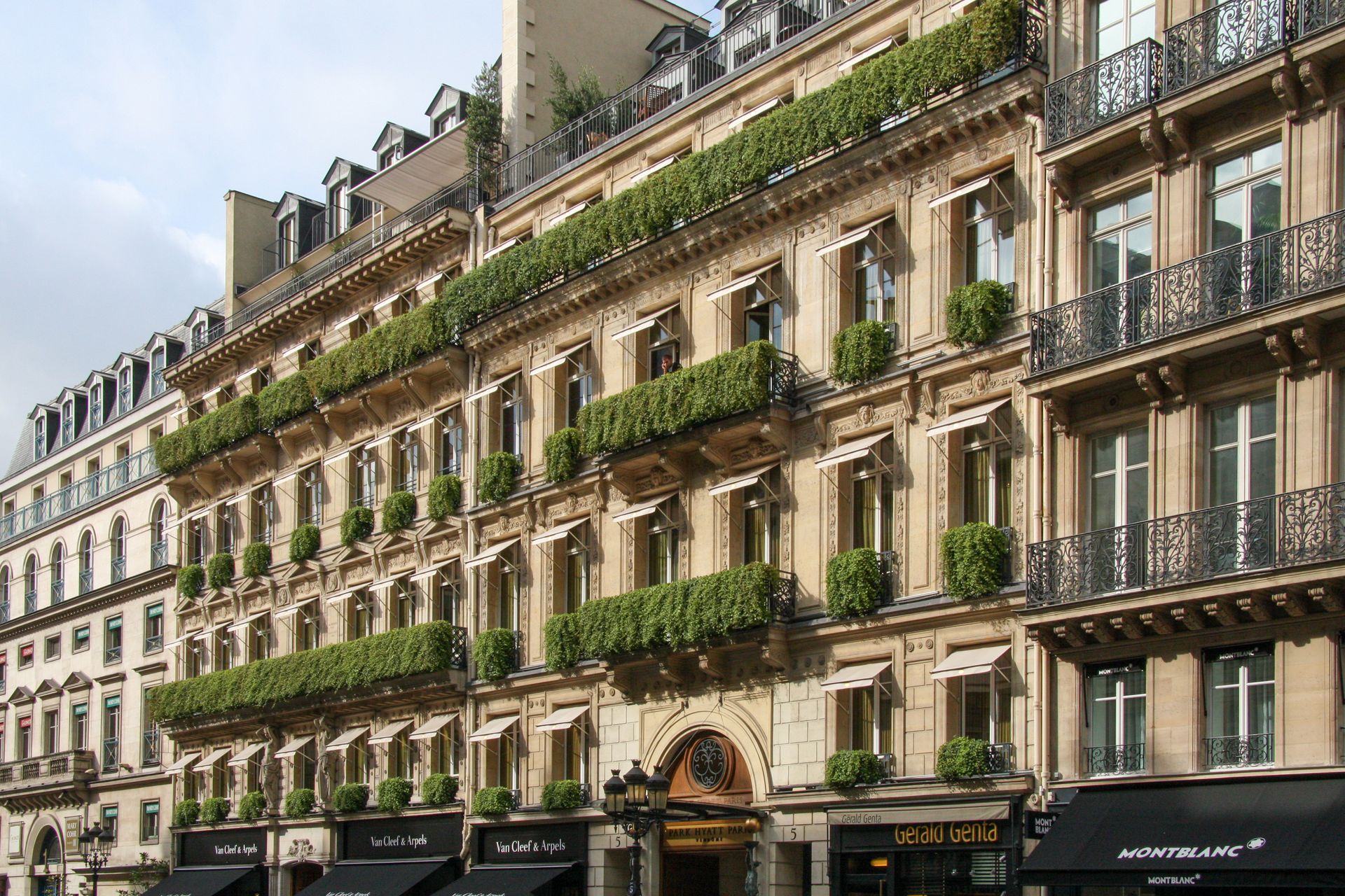 Elegant Parisian building facade with green planters and awnings.