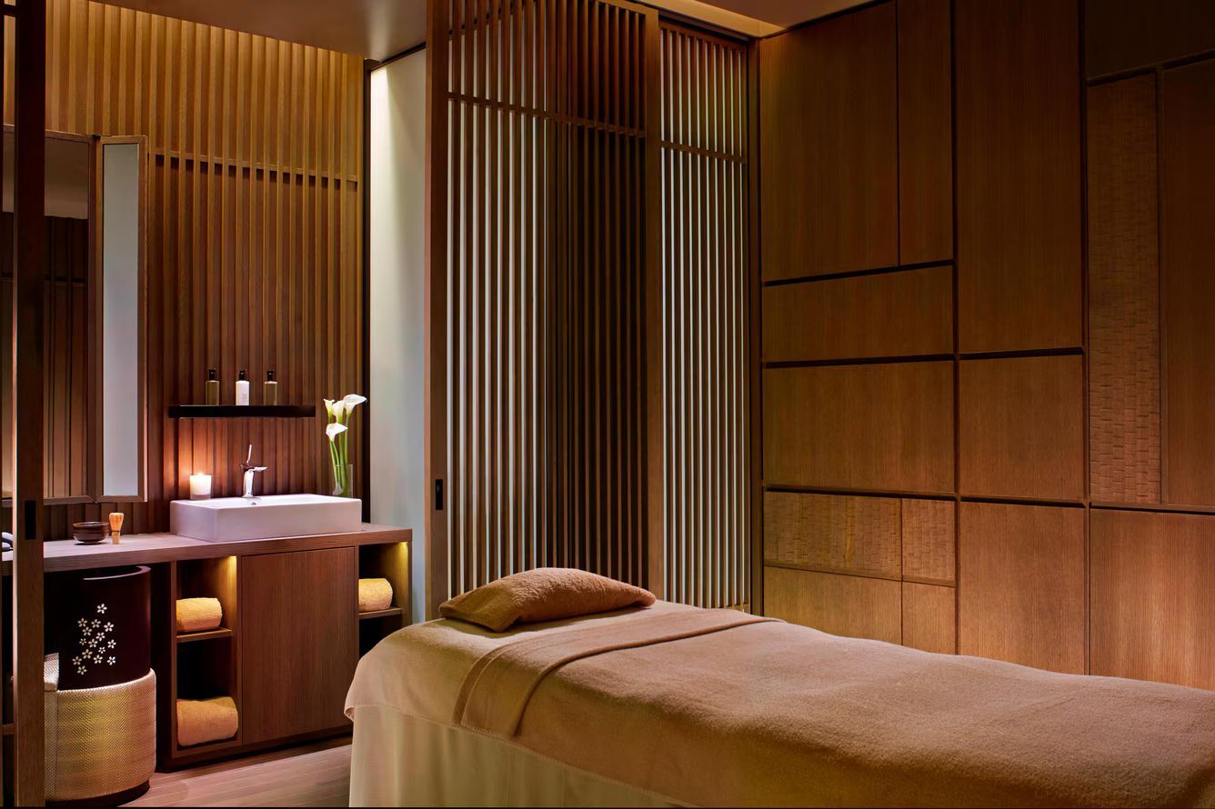 Spa room with massage table, wooden walls, and sink. Ritz-Carlton Kyoto