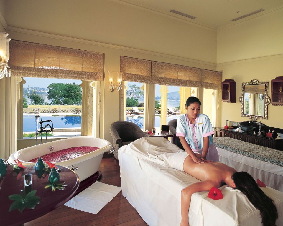 Woman receiving back massage in spa room with pool view.