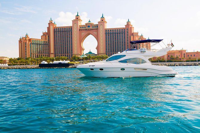 White motor yacht sails on turquoise water in front of the Atlantis resort, Dubai.