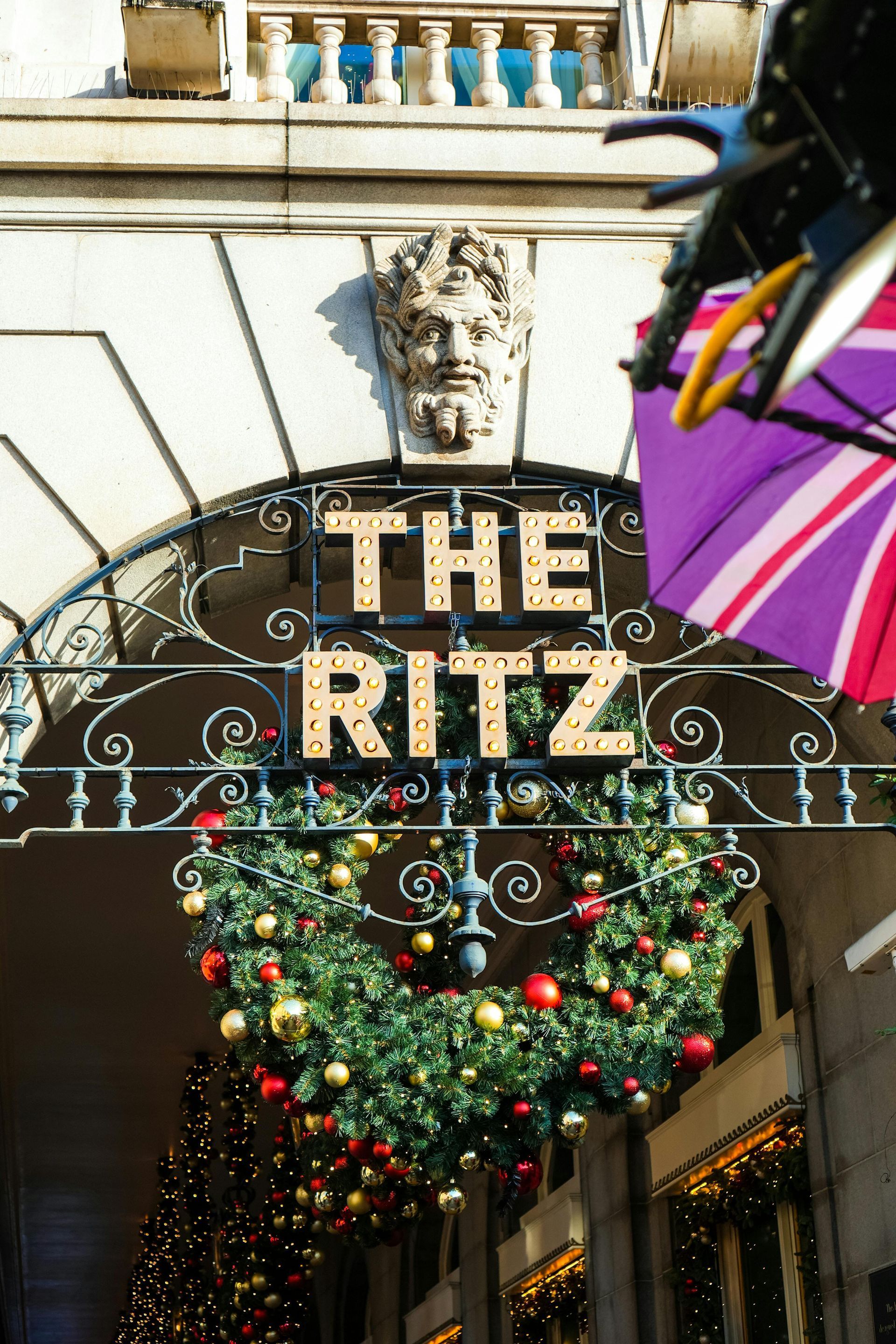 The Ritz hotel entrance with a decorative wreath and a British flag umbrella.