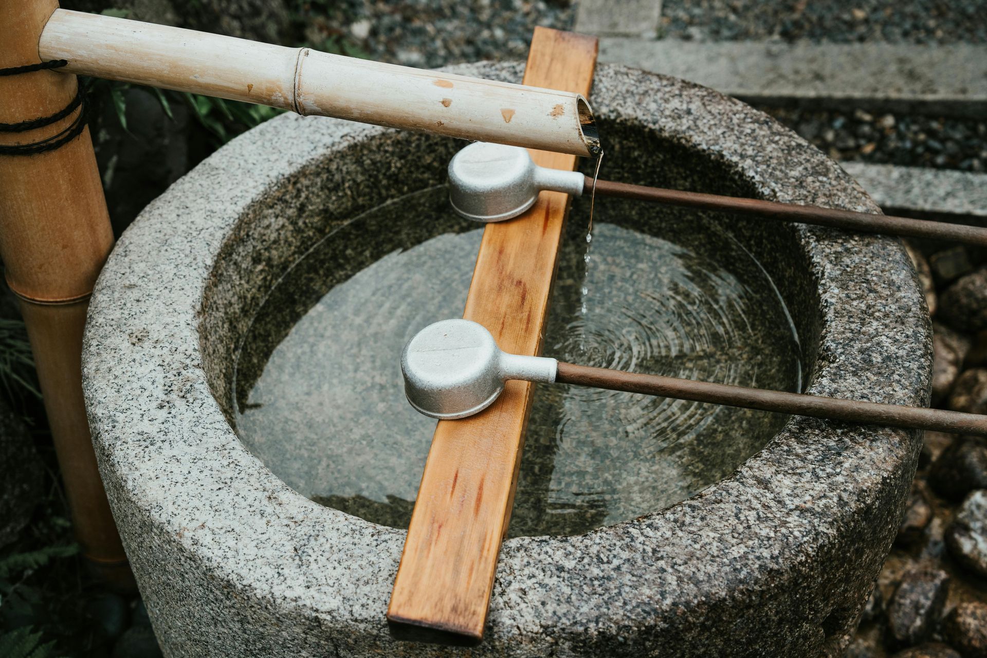 Stone water basin with two bamboo ladles resting on it and water inside