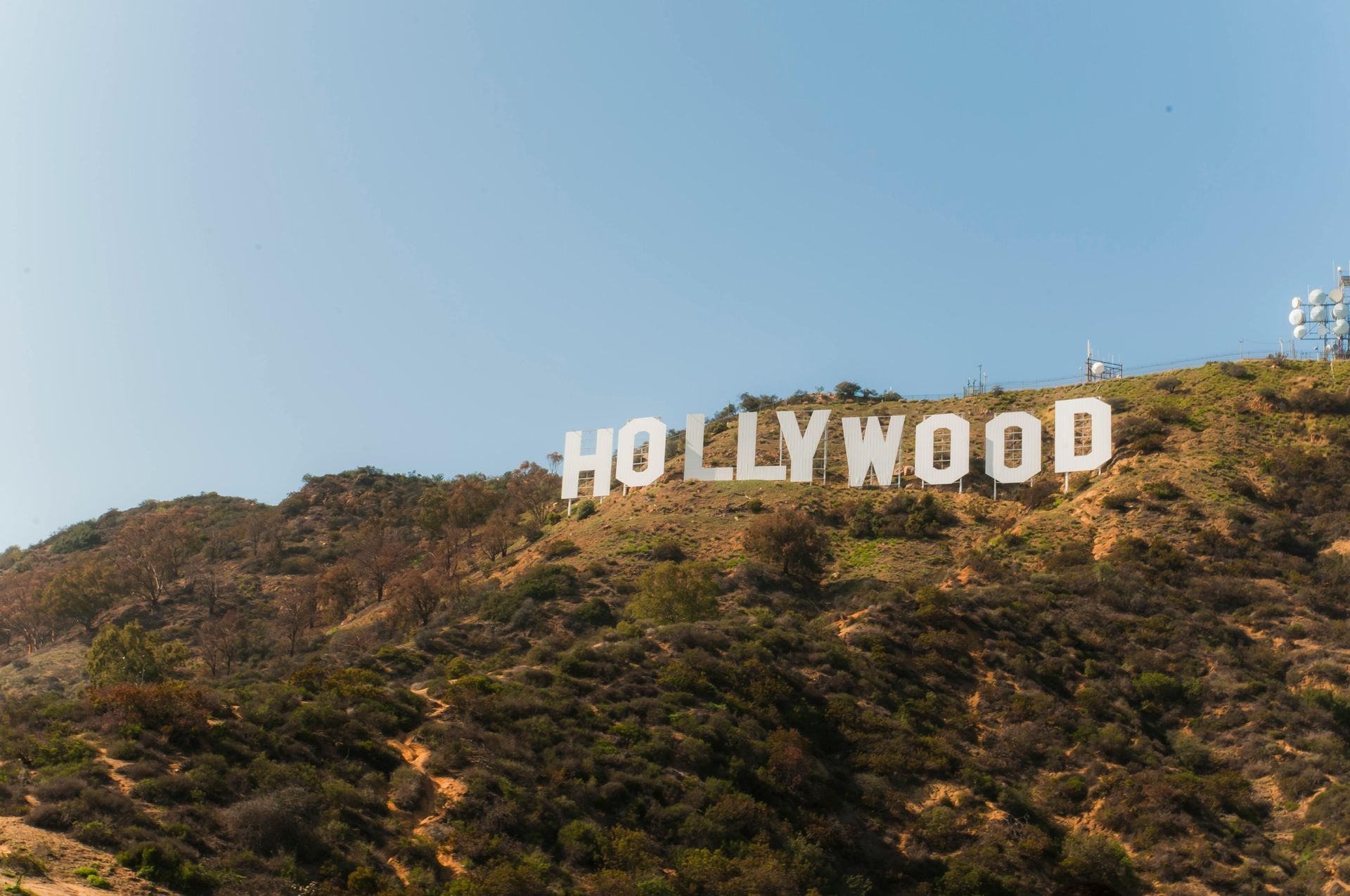 Hollywood sign on a hillside, white letters against a blue sky, sunny day. Beverly Hills 