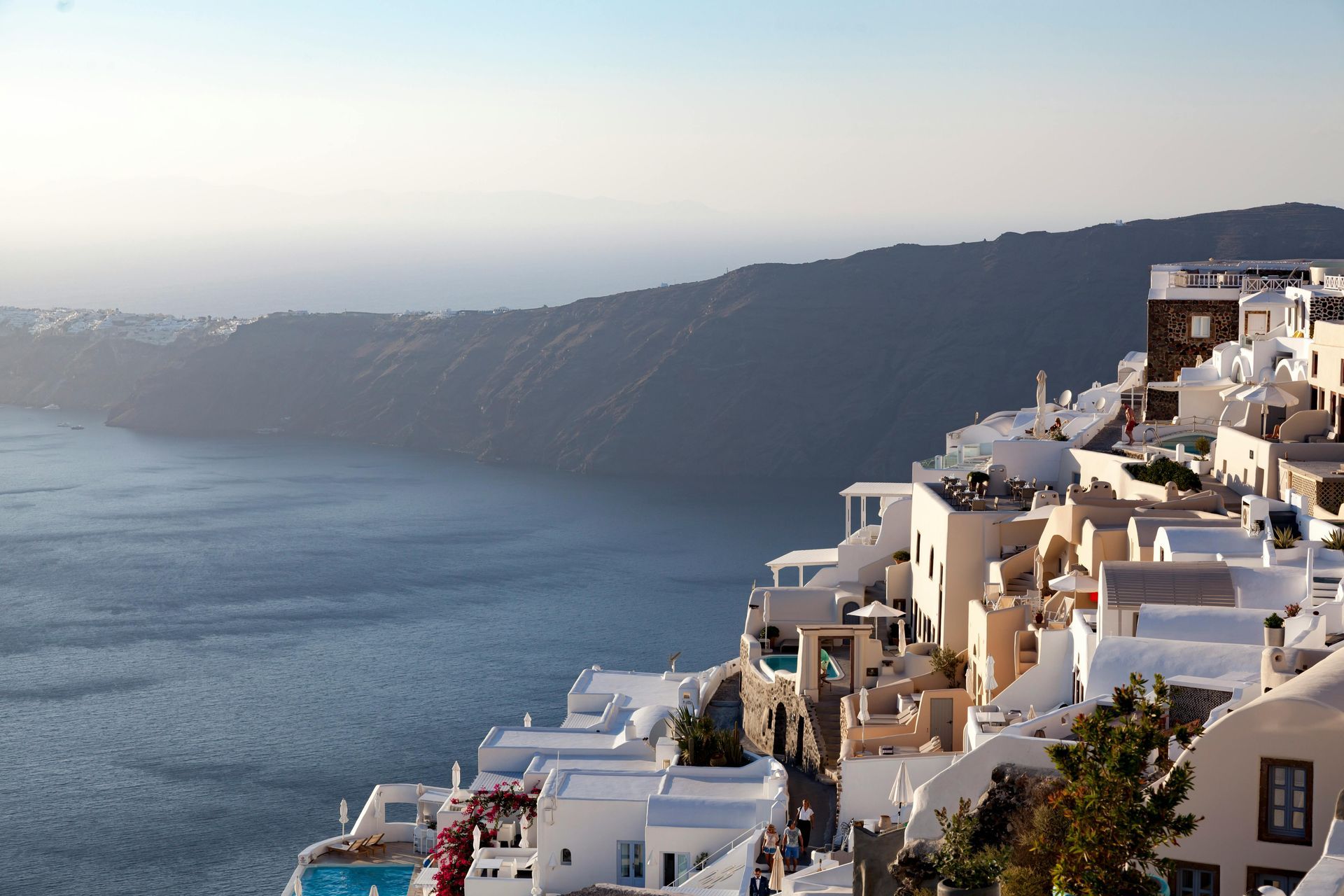 Whitewashed buildings cascading down a cliffside in Santorini, Greece, overlooking the Aegean Sea. Grace Hotel, Auberge Resorts Collection, Imerovigli