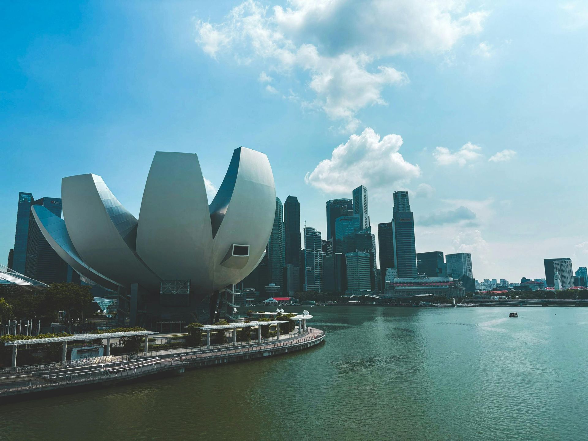 The ArtScience Museum, shaped like a white lotus flower, stands along the waterfront near the Singapore city skyline.