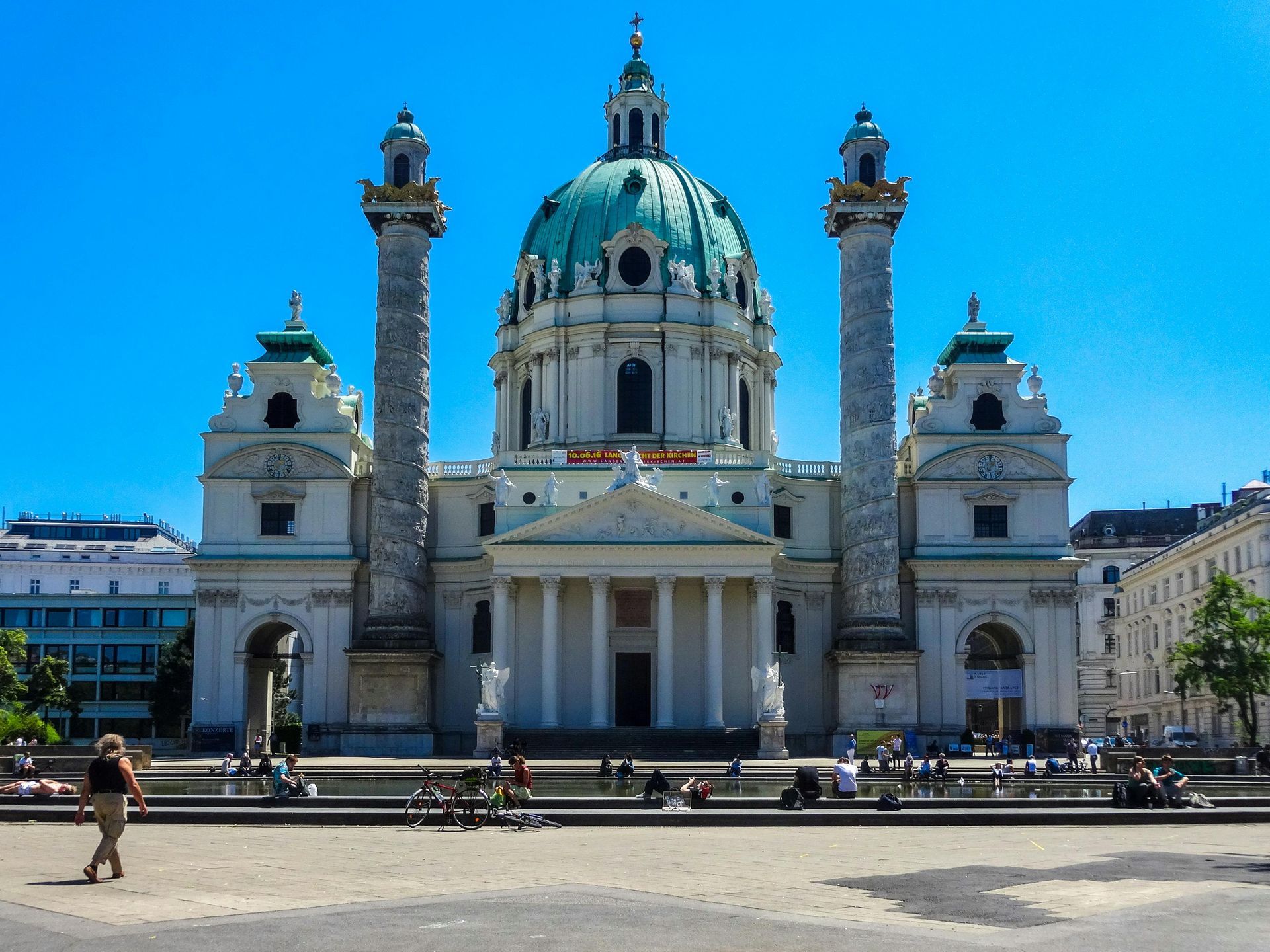 Grand historic cathedral with green dome and twin columns under a clear blue sky in a city square Vienna