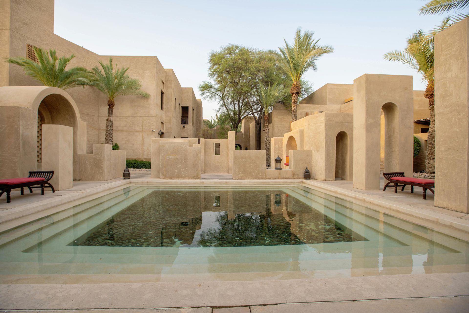A courtyard with a pool, beige buildings, and palm trees.