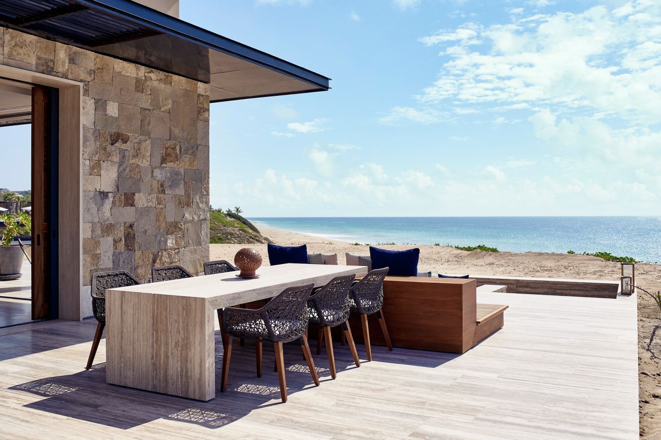 Modern seaside patio with outdoor dining table, chairs, and ocean view Zadún, a Ritz-Carlton Reserve
