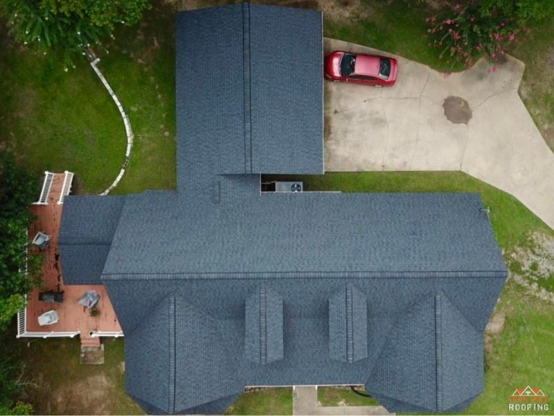 Top-down aerial view of a house with a dark gray shingled roof, a red car in the driveway, and a wooden deck.