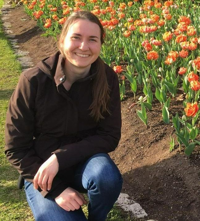 A woman is kneeling down in front of a field of flowers