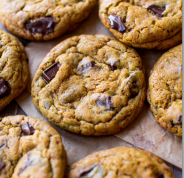 A bunch of chocolate chip cookies are sitting on a table.