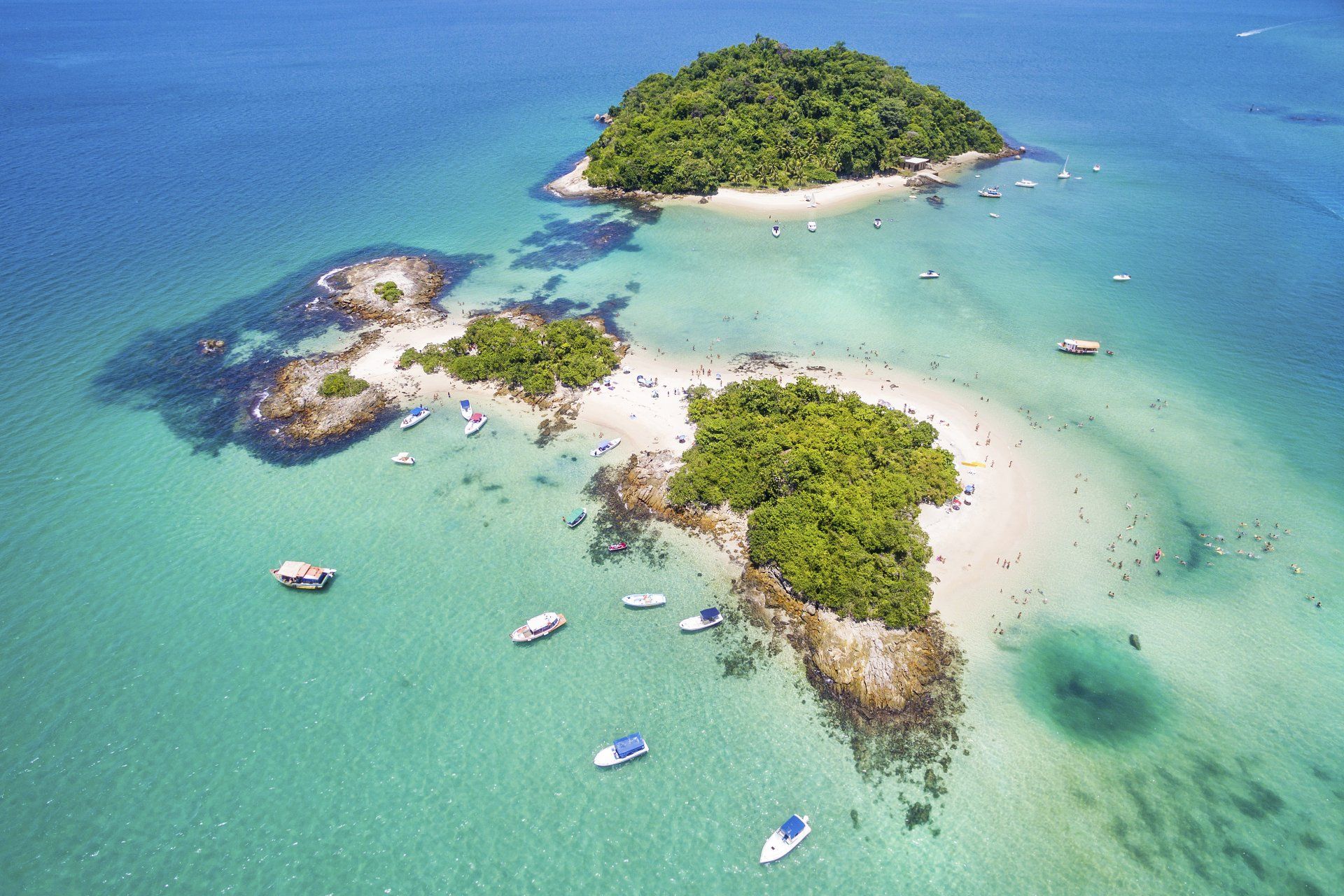Uma vista aérea de uma pequena ilha no meio do oceano cercada por barcos.