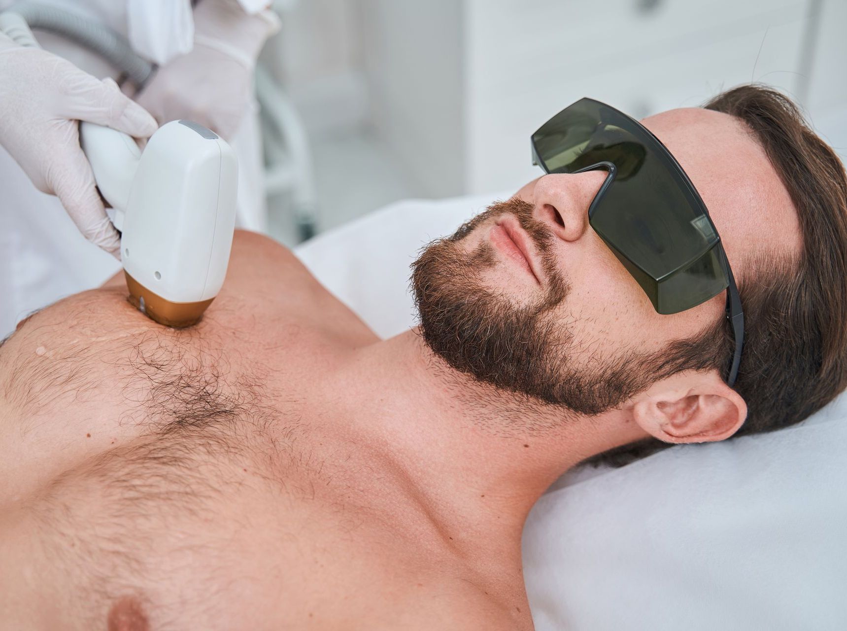 Ein Mann mit Bart lässt sich auf der Brust eine Laser-Haarentfernung durchführen.