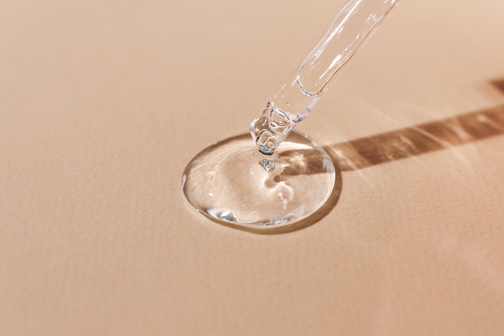 Ein Tropfen Flüssigkeit wird aus einer Pipette in ein Glas gegossen.