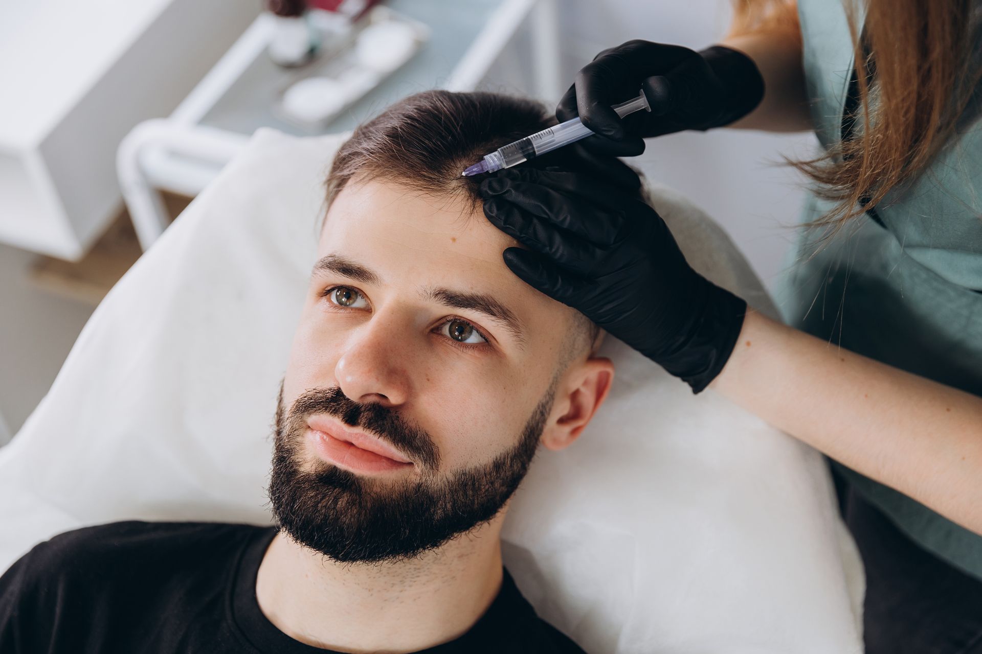 Ein Mann mit Bart bekommt in einem Salon eine Haarbehandlung.