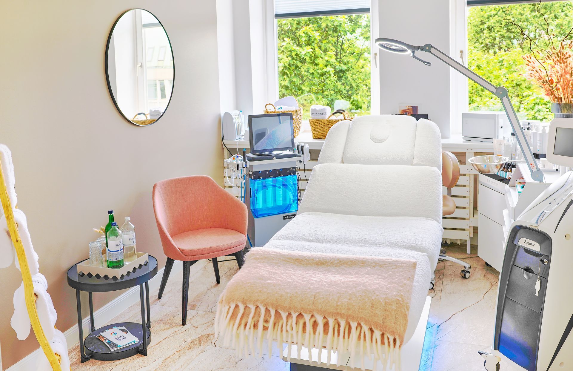 Spa-Behandlungsraum mit weißer Behandlungsliege, Stuhl und Ausstattung.