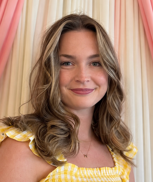 Smiling woman in a yellow dress before pastel drapes