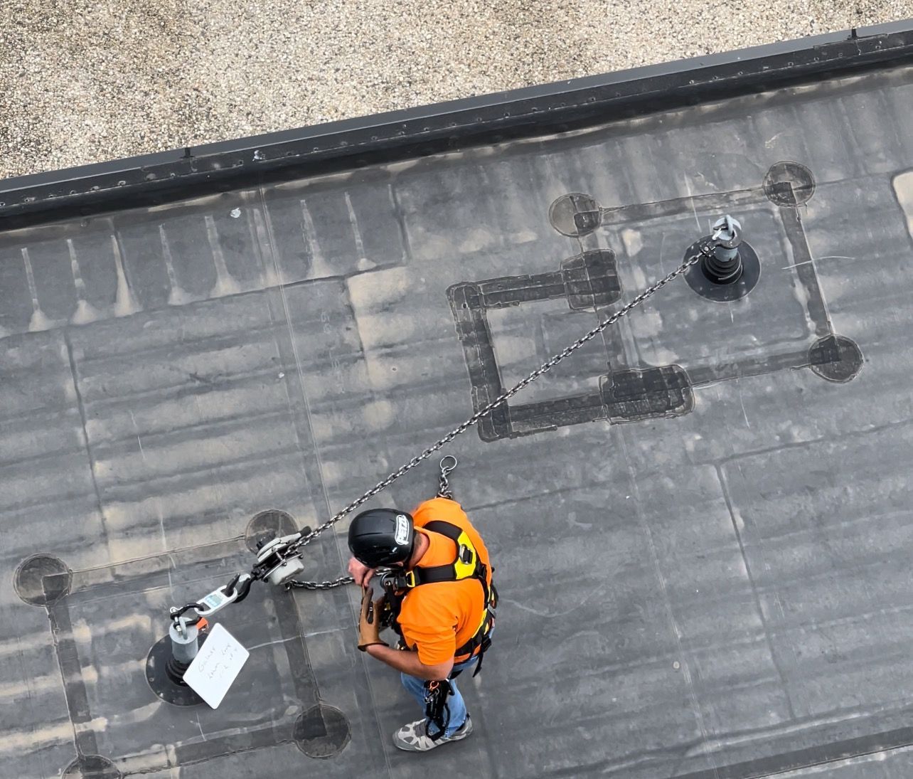 A man is standing on a roof with a harness on