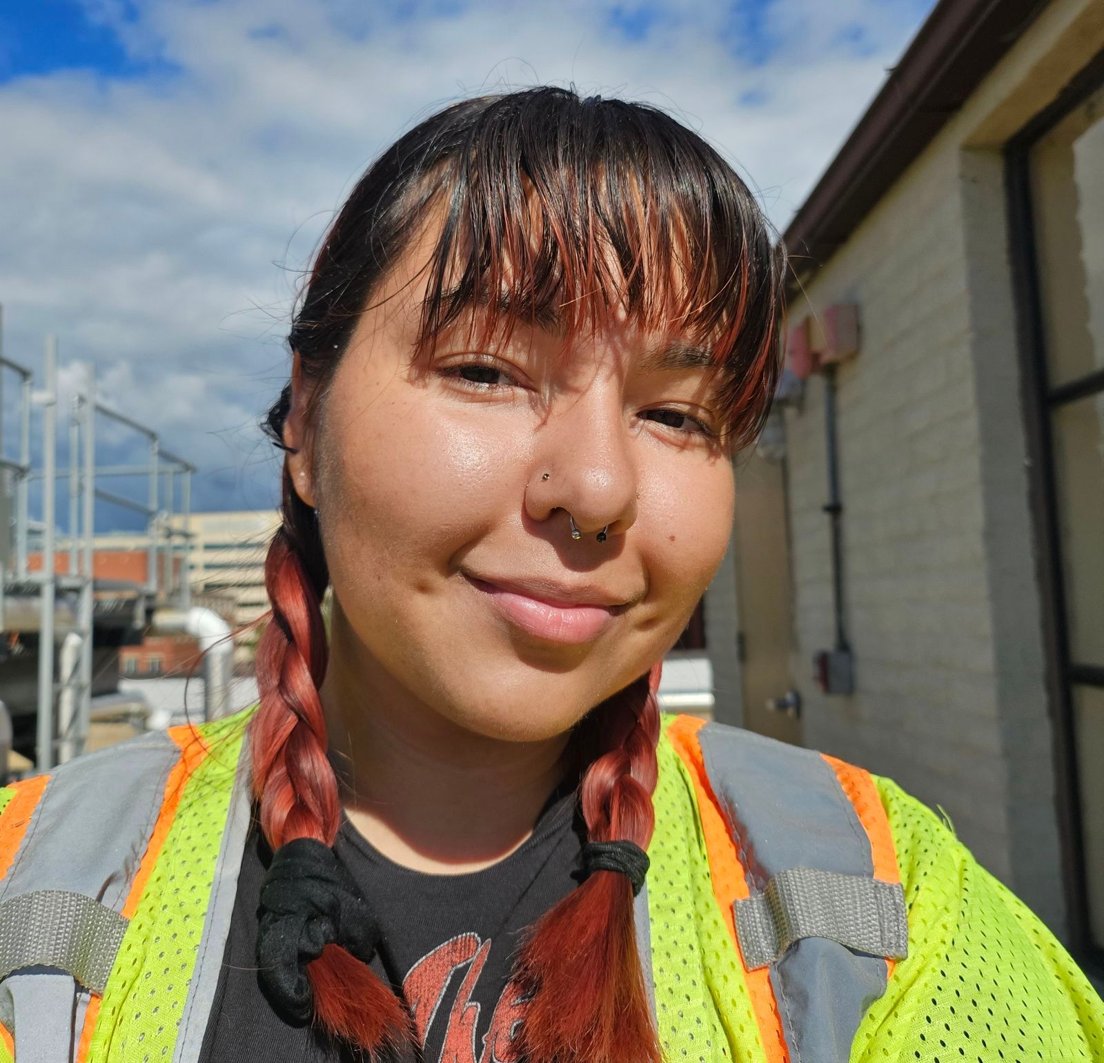 Person in a neon safety vest smiling outdoors in bright sunlight
